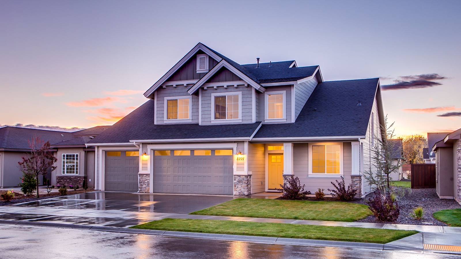 A well kept two story home at golden hour, warm light on the front and a green lawn